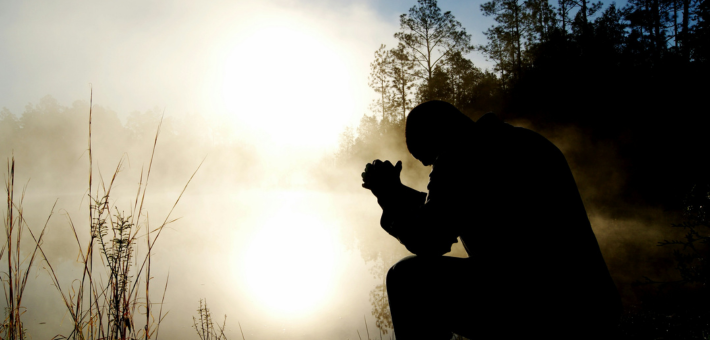 photo of a man in silhouette praying