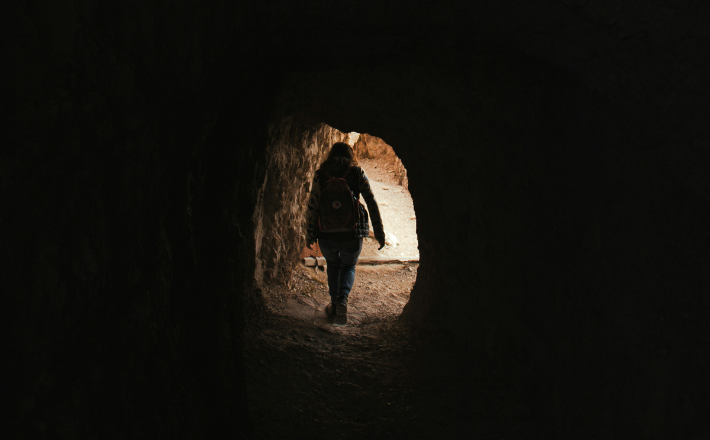 A person walking out of a dark tunnel.