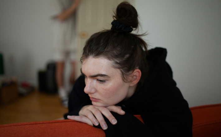 A woman sitting on a couch looking down.