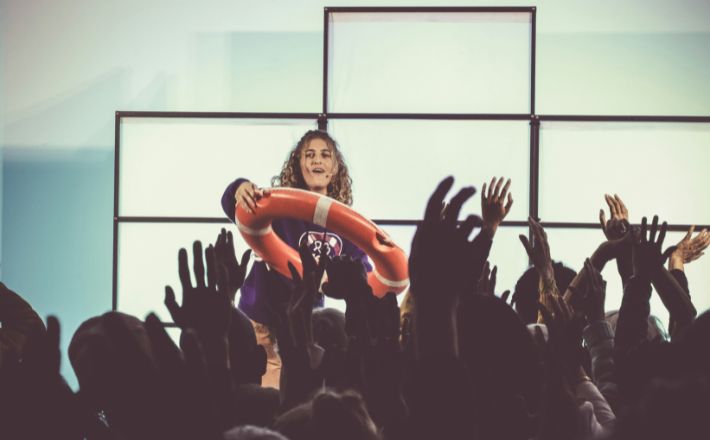 Young woman throwing lifesaving buoy to crowd