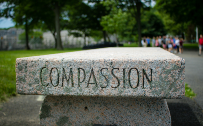 Gray concrete bench with the word compassion inscribed.