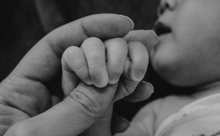 Parent hand holding baby hand near baby's head
