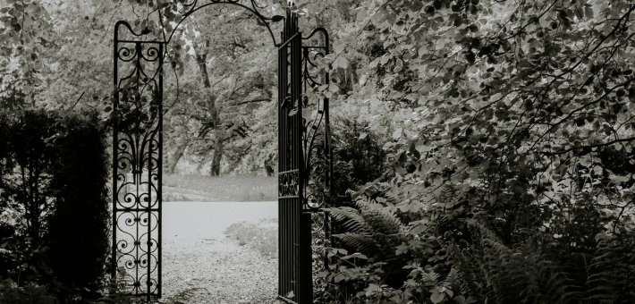 black and white photo of an open garden gate