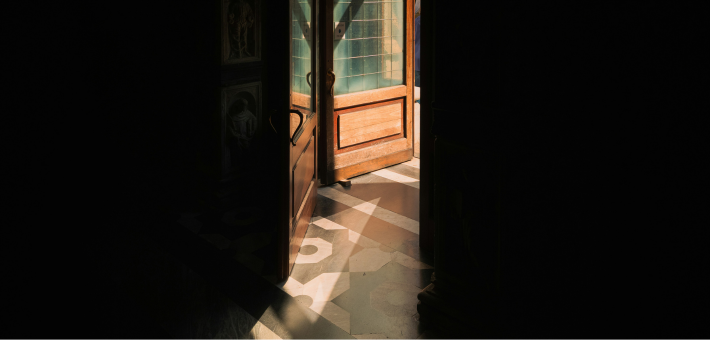 photo of a door in a dark room opening to light