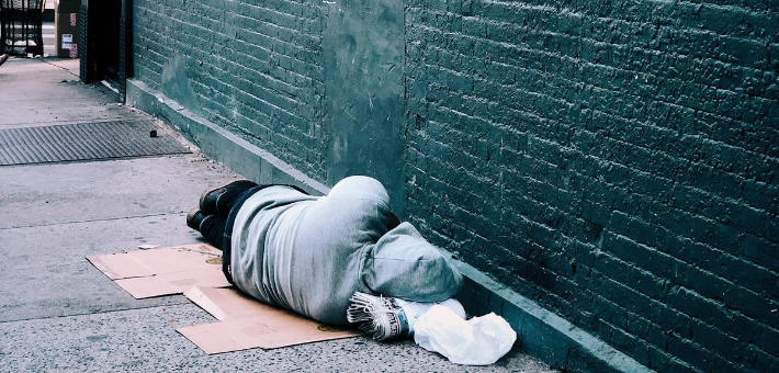 photo of a man sleeping on new york city street, facing a wall